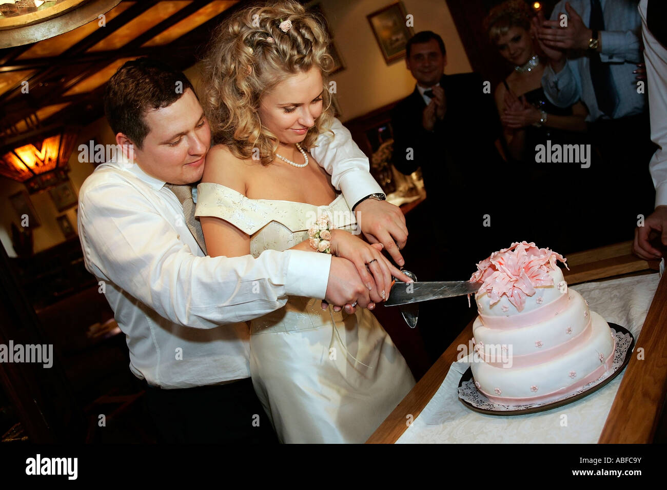 Une vue générale d'un couple nouvellement marié couper un gâteau de mariage à l'accueil Banque D'Images