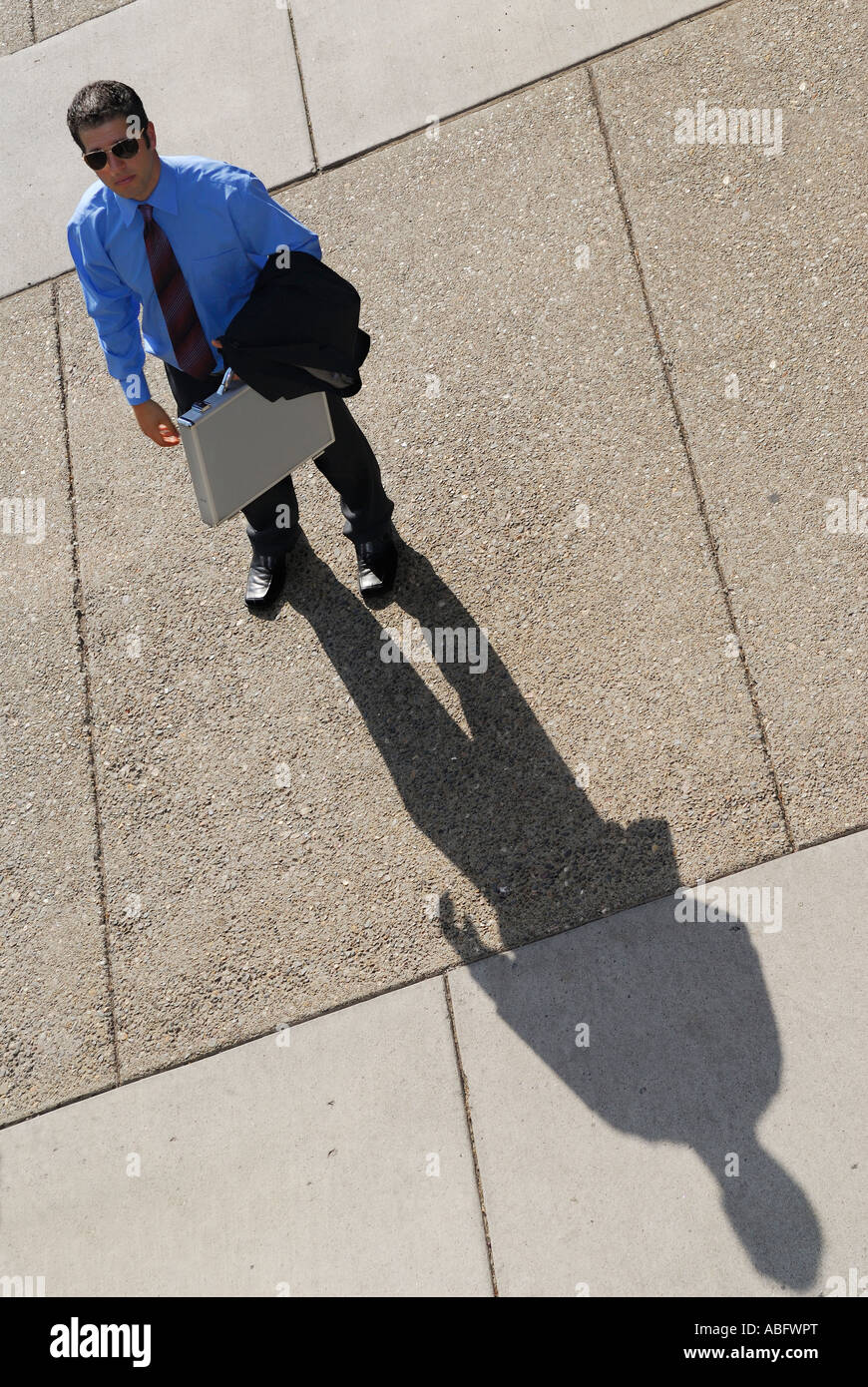 Businessman avec ombre debout sur une cour intérieure en béton Banque D'Images