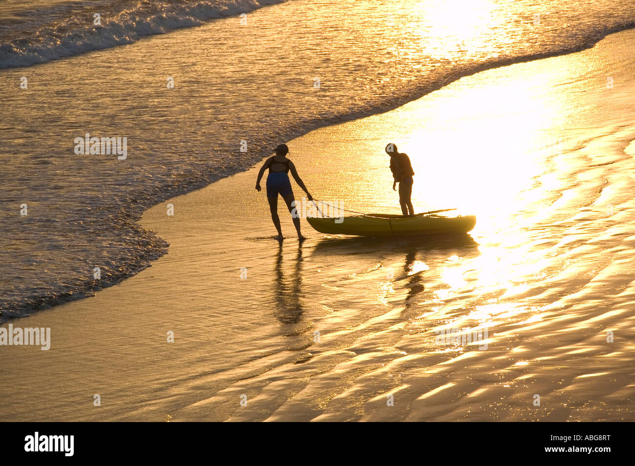 Coucher de soleil rouge avec deux personnes et de canoë sur la plage. Banque D'Images