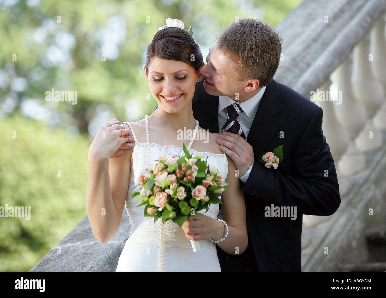 La promise dans une robe de mariée blanche traditionnelle ici vu sourire comme son mari embrasse son. Banque D'Images