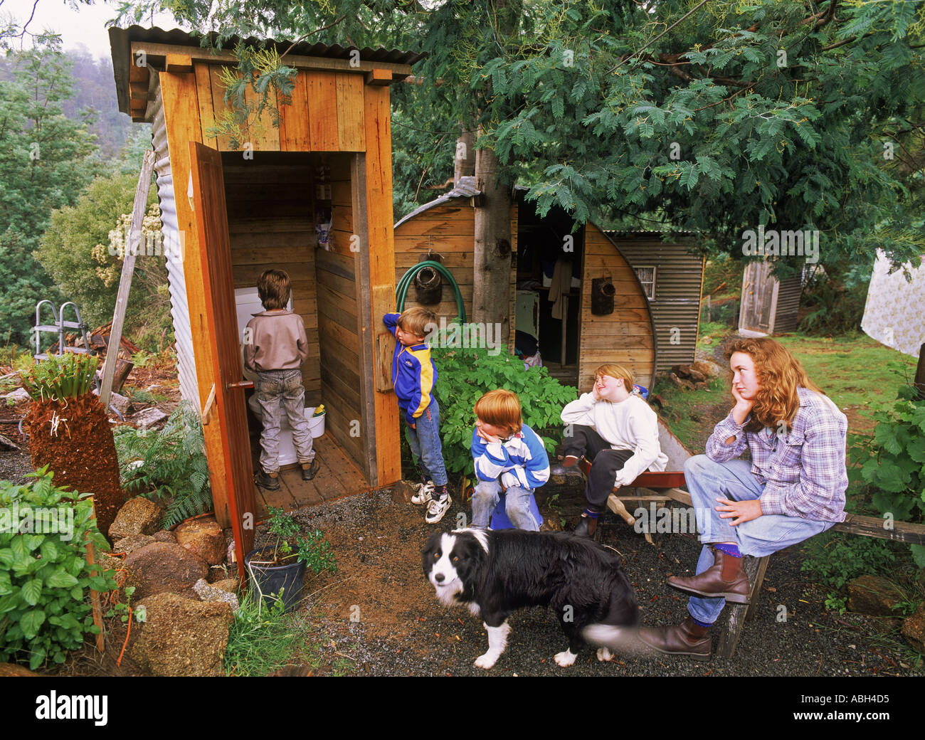 Enfants et maman en attente d'utilisation famille dunny ou outhouse en pays accueil jardin en Tasmanie en Australie Banque D'Images