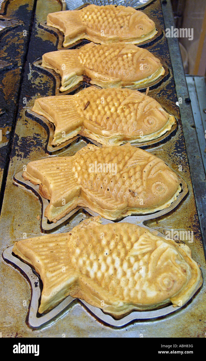 Rempli de haricots rouges en forme de poisson taiyaki bonbons battues la cuisson sur une plaque chaude dans un marché d'alimentation au Japon Banque D'Images