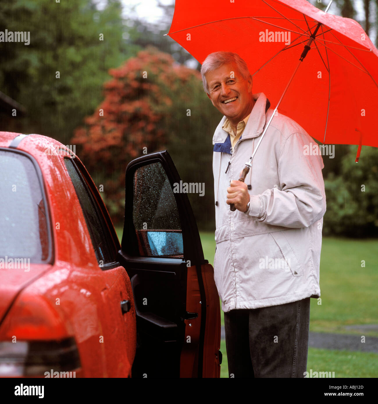 Avec l'homme debout à côté d'PARAPLUIE VOITURE SOUS LA PLUIE Banque D'Images