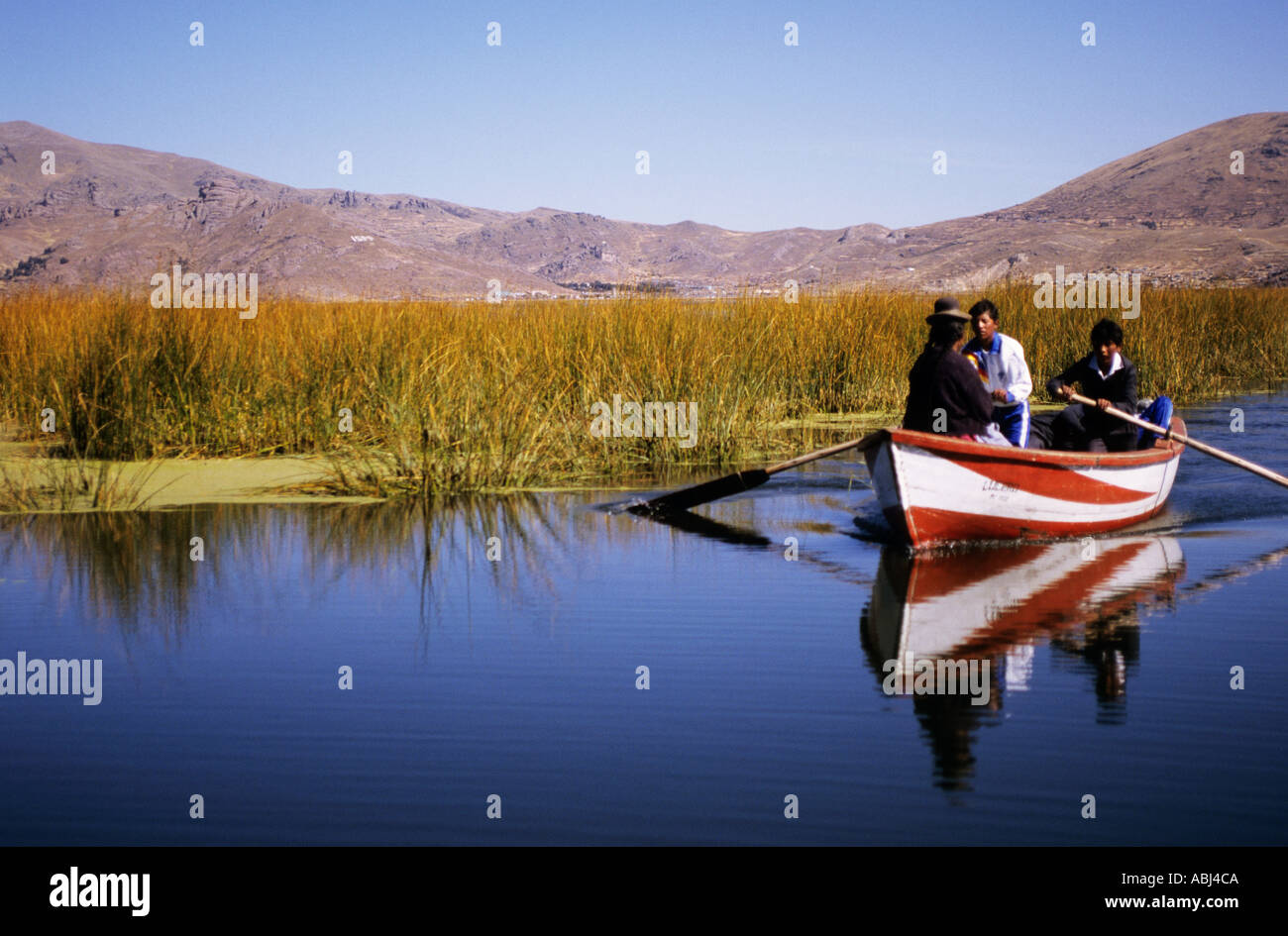 Le lac Titicaca, au Pérou. Deux hommes et une femme dans un bateau rouge et blanc sur le lac. Banque D'Images