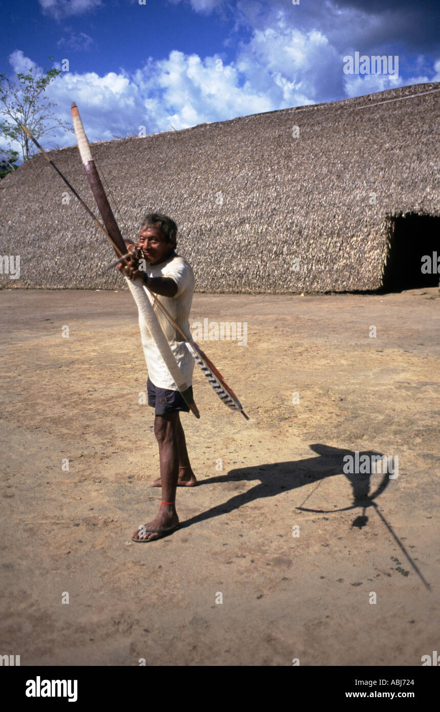 Village Koatinemo, au Brésil. Assurini indien démontrant son arc et flèche compétences à l'extérieur de la Chambre des morts. L'État de Para. Banque D'Images
