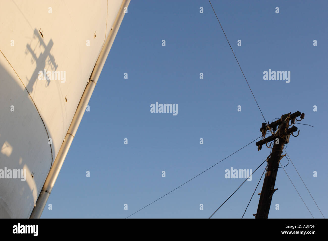 Poteau télégraphique d'ombre et silhouette contre le ciel bleu et le réservoir de stockage à l'usine de levure Bio-sciencen Kerry à Menstrie. Banque D'Images