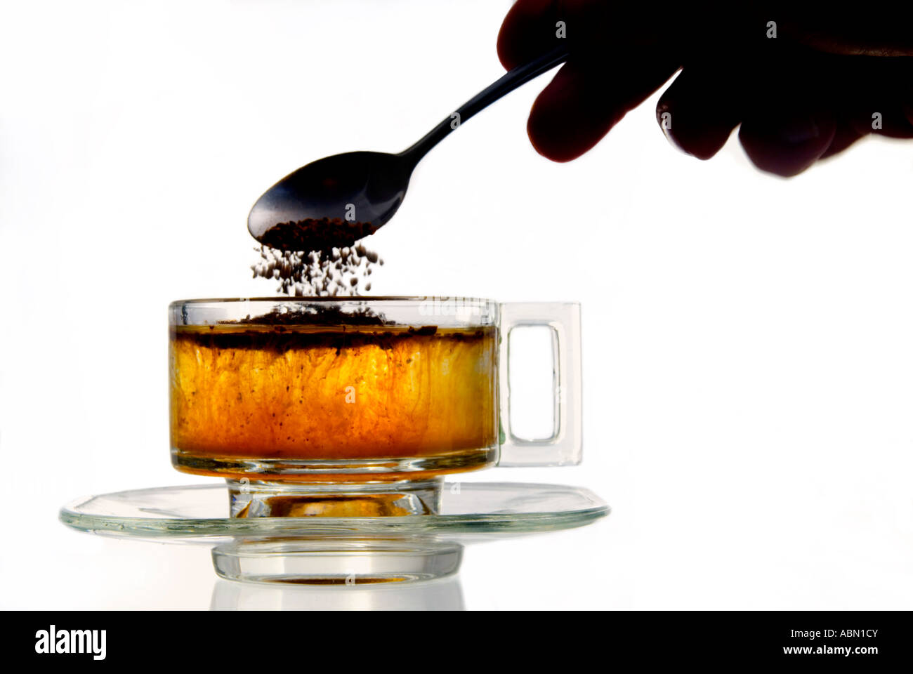 Le café instantané ajouté à l'eau dans une tasse en verre Banque D'Images