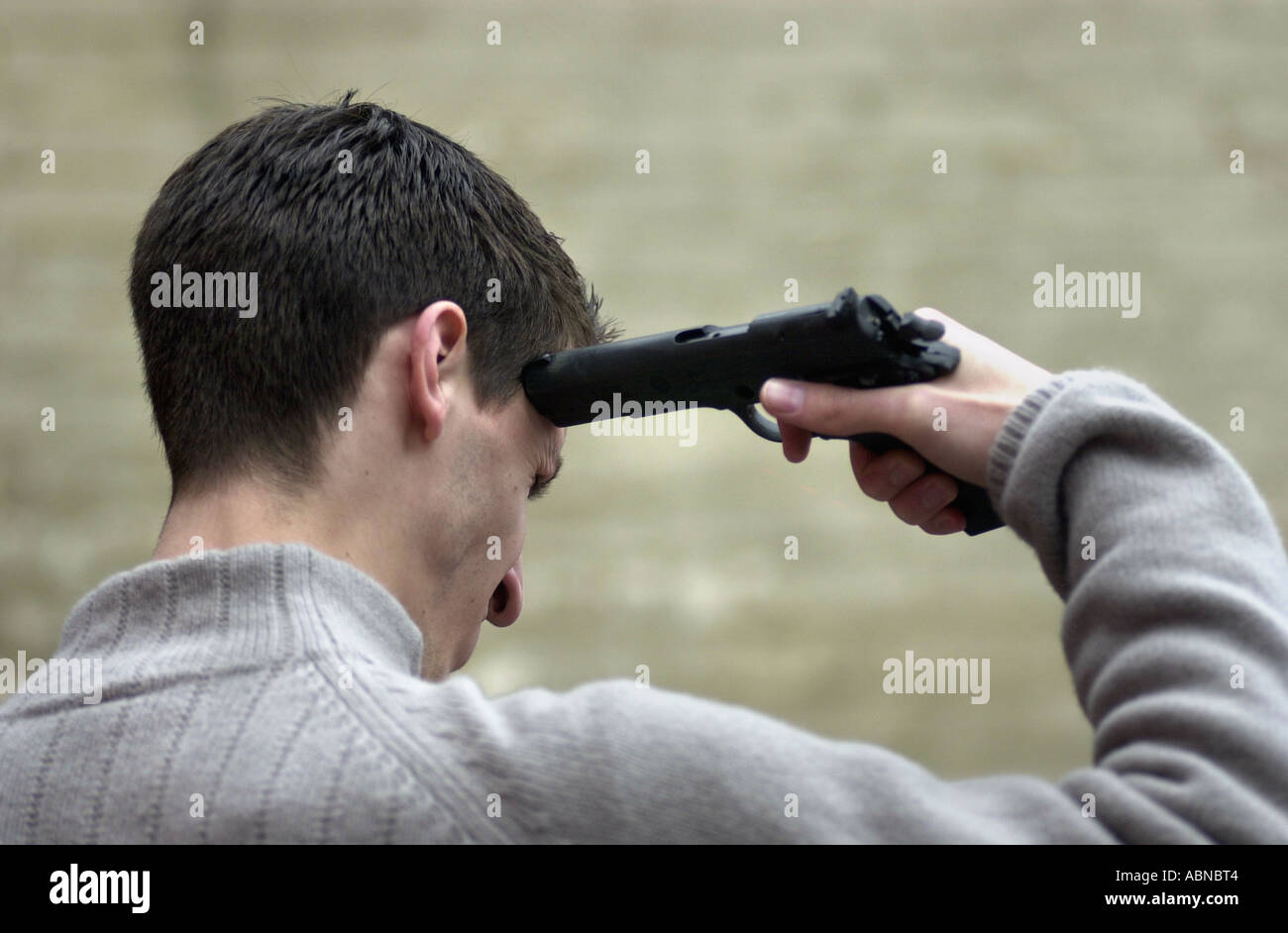 Jeune homme cherche un pistolet à sa tête dans un suicide posent UK Banque D'Images