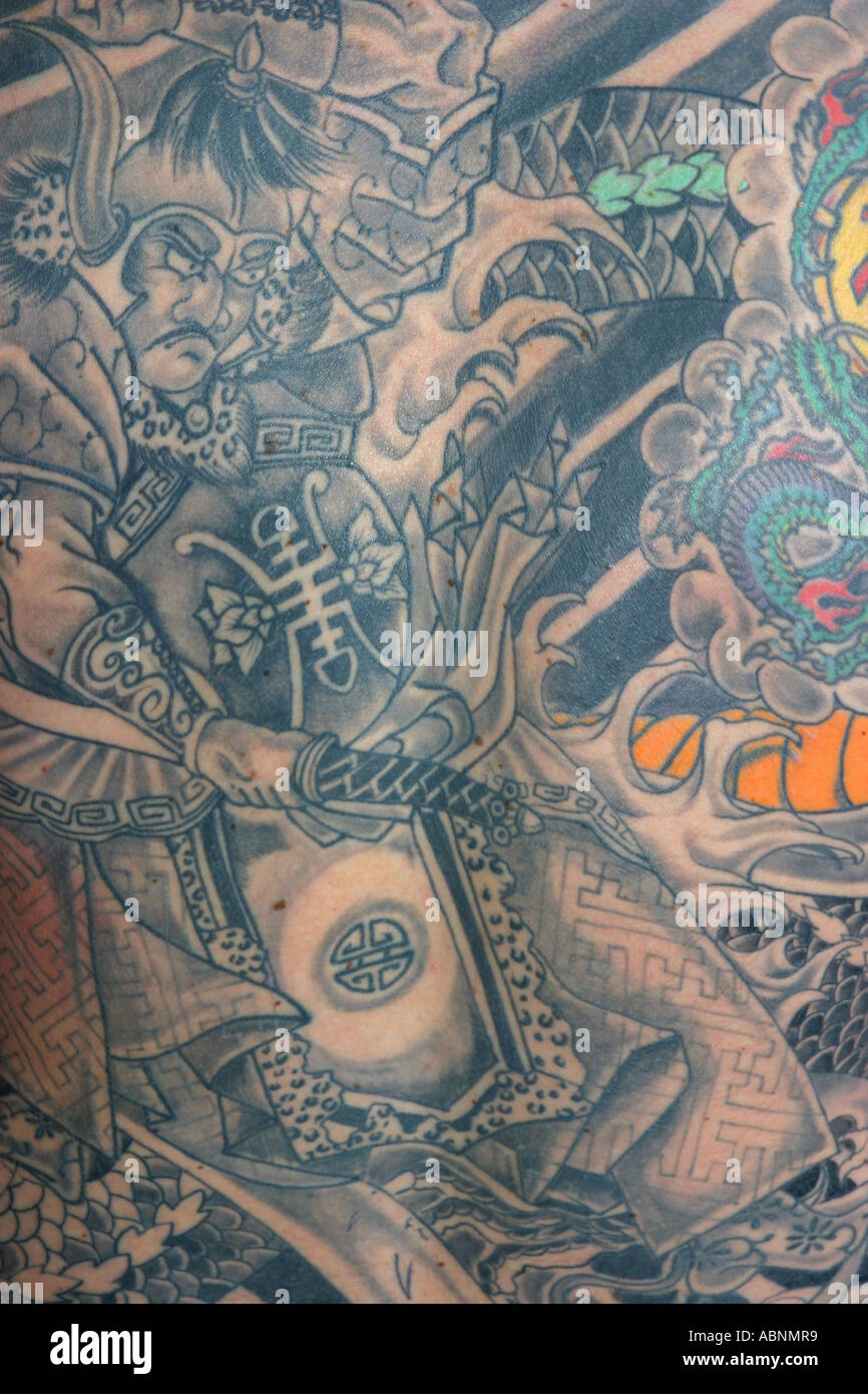 Un retour de l'homme visés dans le tatouage y compris un dragon, samouraï et le vent des bars. Banque D'Images Un retour de l'homme visés dans le tatouage y compris un dragon, samouraï et le vent des bars. Banque D'Images