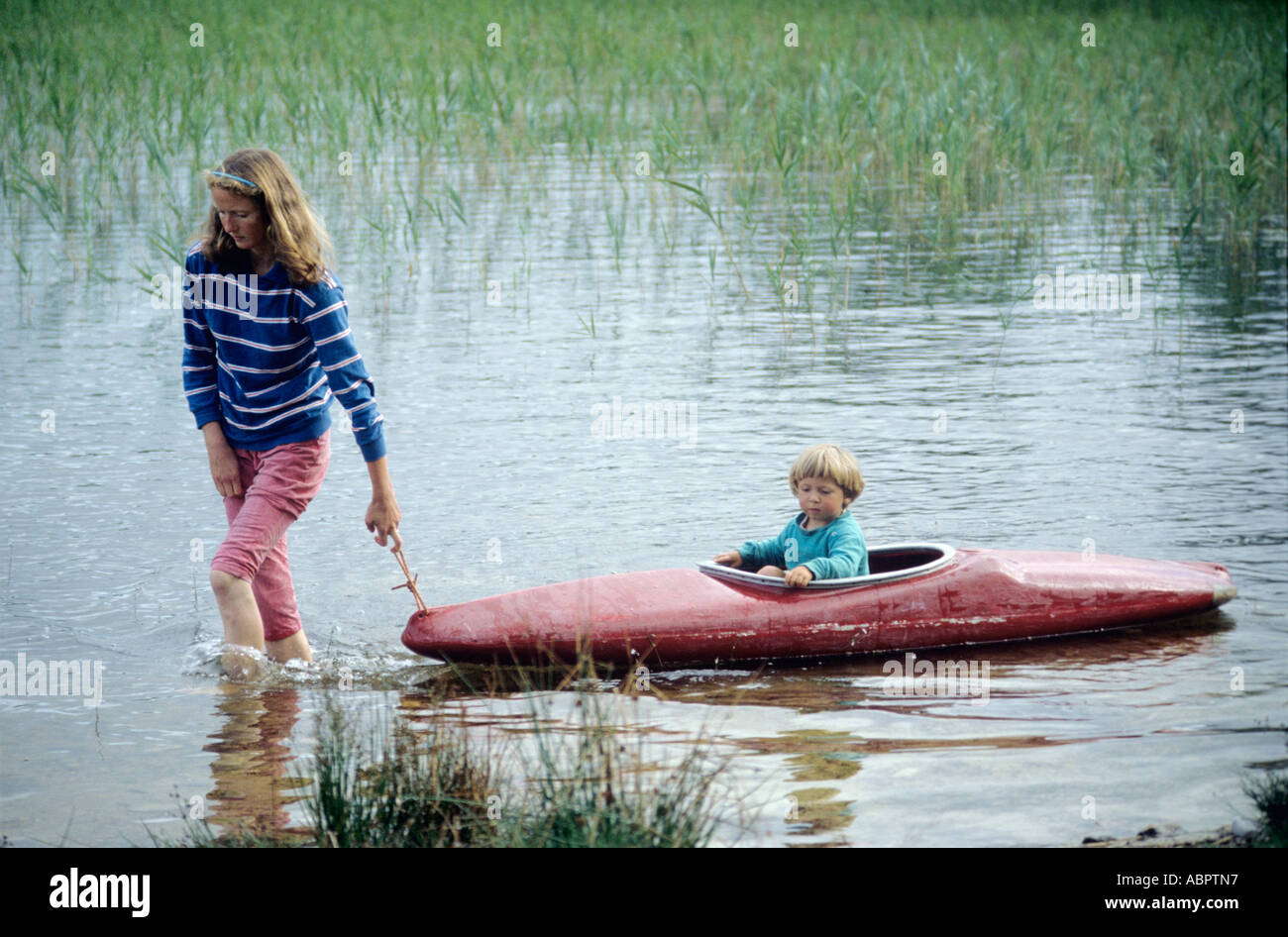 Mère Enfant tirant dans un kayak rouge sur un loch dans les highlands écossais Banque D'Images