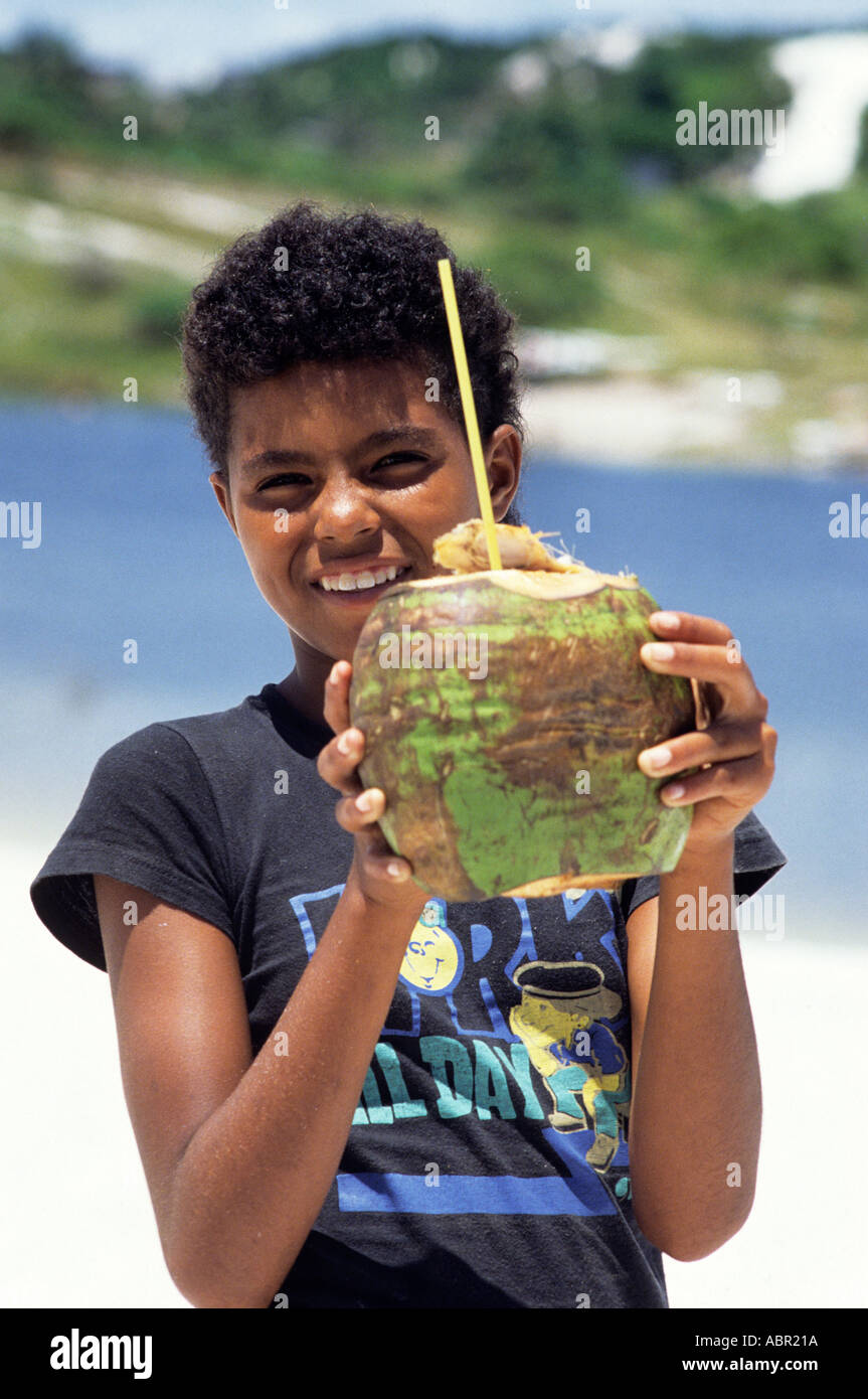 Salvador, Bahia, Brésil. Smiling boy holding une noix de coco avec une paille en elle, prêt à boire. Banque D'Images