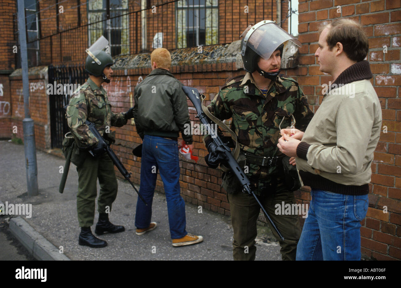 Troupes britanniques les troubles des années 1980, soldats armés de l'armée britannique en patrouille à pied, arrêter et fouiller les hommes dans la rue. Belfast Irlande du Nord 1981 Royaume-Uni. Banque D'Images