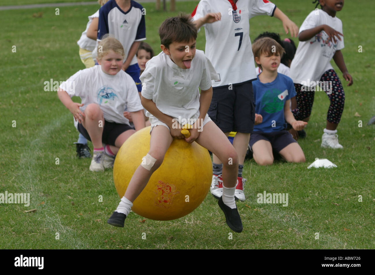 Une école primaire garçon saute sur un ballon sauteur au cours d'une journée du sport scolaire, Clissold Park, Londres, UK. Banque D'Images