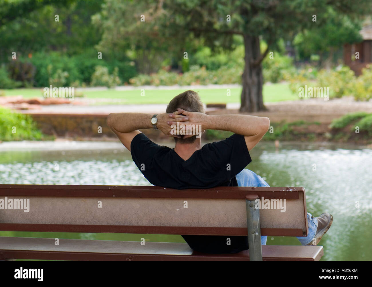 Jeune homme caucasien se remet en marche, se détend, rêve et se déroule assis sur un banc dans un parc à Oklahoma City, Oklahoma, USA. Banque D'Images
