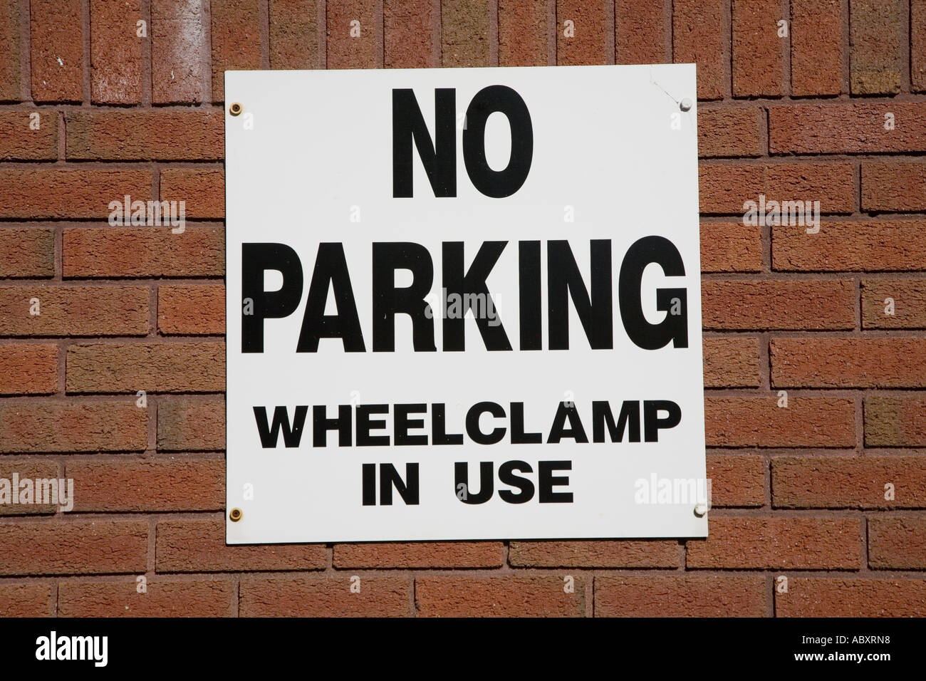 Pas de parking privée dans wheelclamps, connectez-vous sur mur de brique Wales UK Banque D'Images