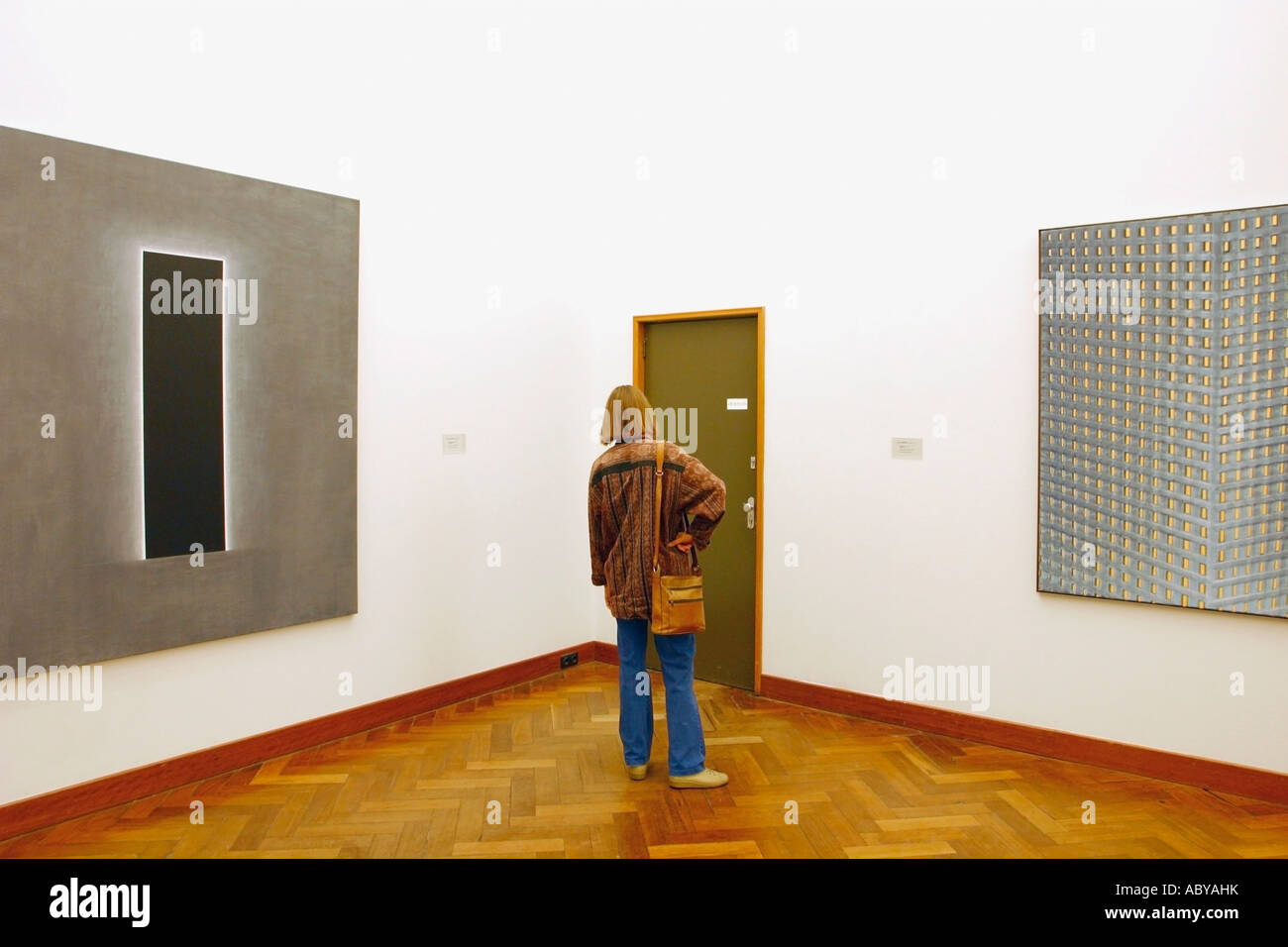 Amsterdam, Hollande. Exposition d'art moderne dans le musée. Femme regardant porte entre deux tableaux modernes. Banque D'Images