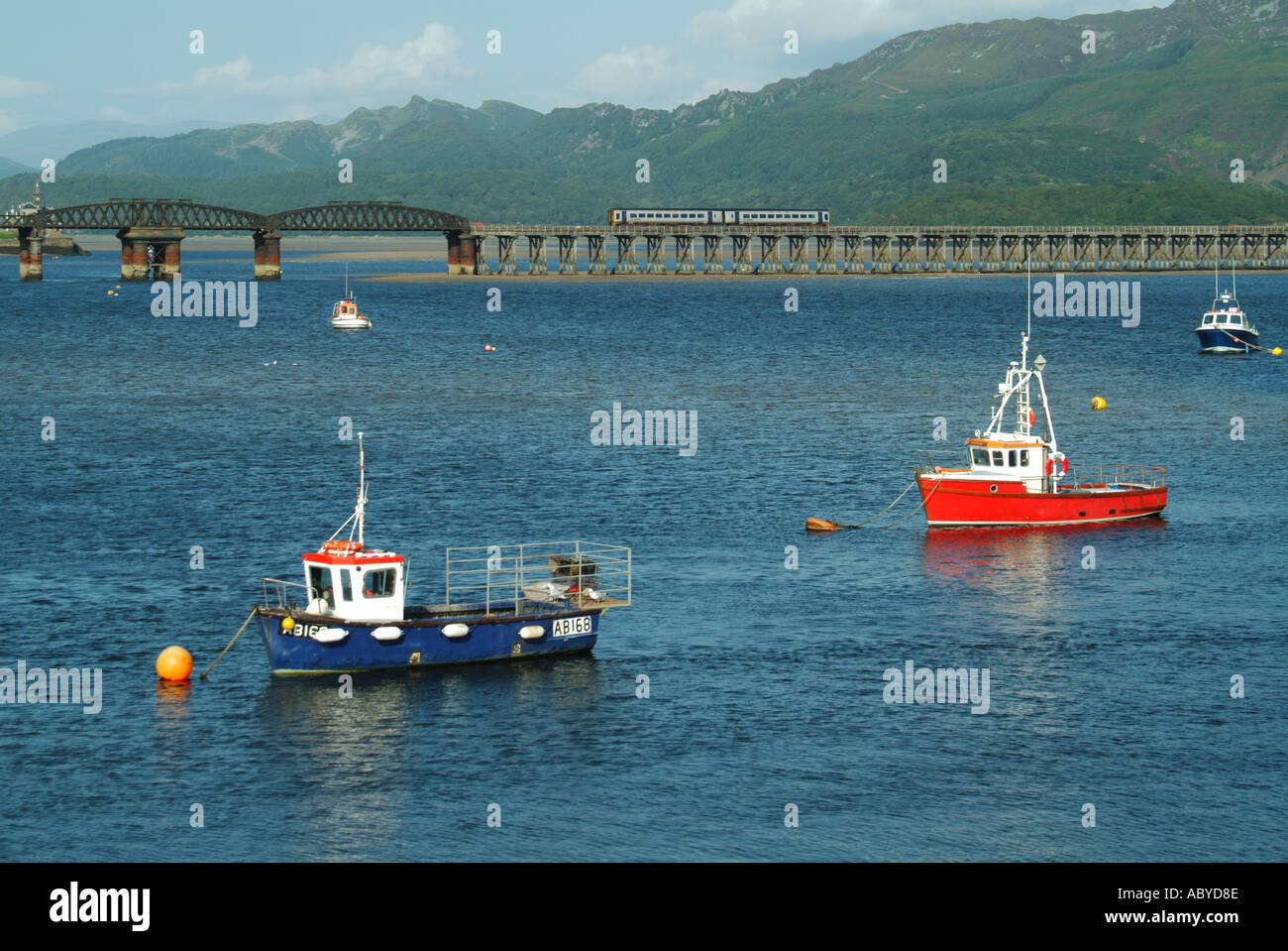 Les bateaux de pêche amarrés Barmouth et petits yachts amarrés dans l'estuaire de Mawddach Afon viaduc de chemin de fer et au-delà de la passerelle Banque D'Images