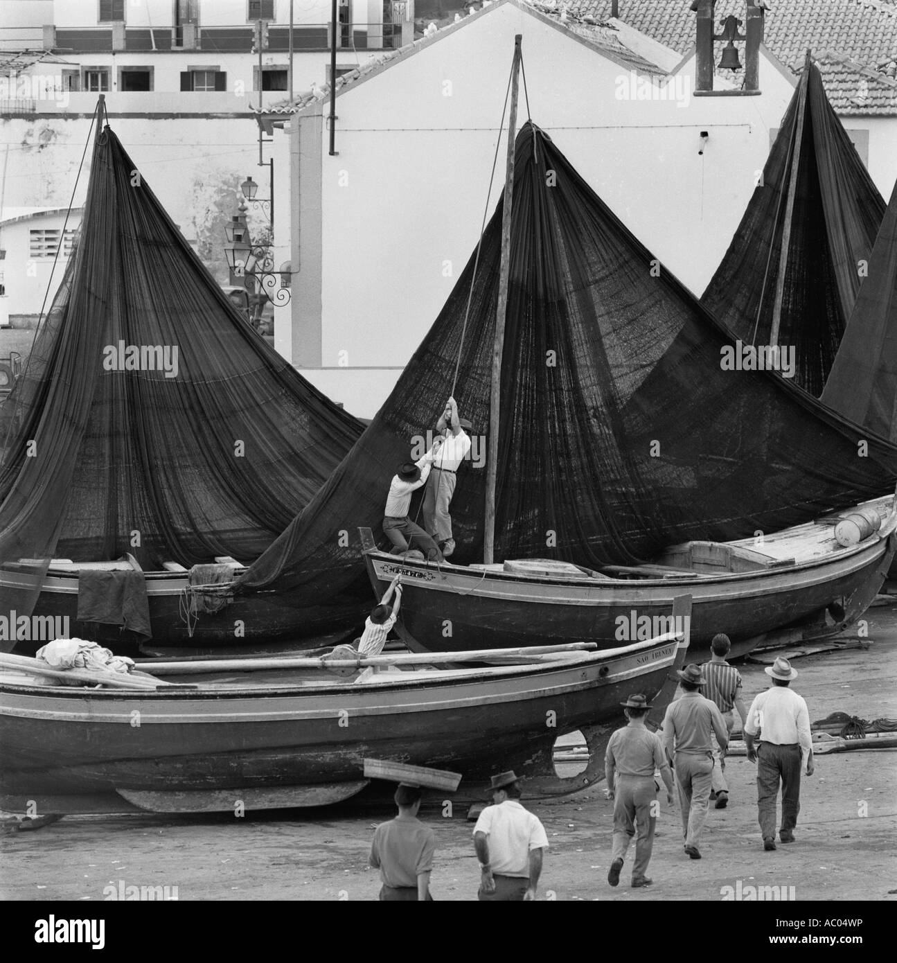 Les pêcheurs tirant leurs filets sur les poteaux pour les sécher au village de pêcheurs de Camara de Lobos, Madère en 1967 Banque D'Images