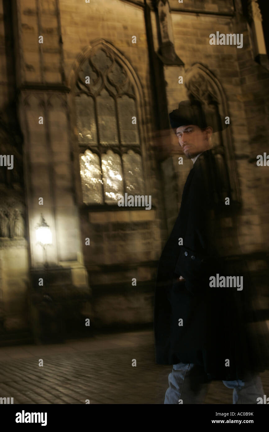 La figure fantomatique d'un homme en passant devant une église de nuit. Banque D'Images