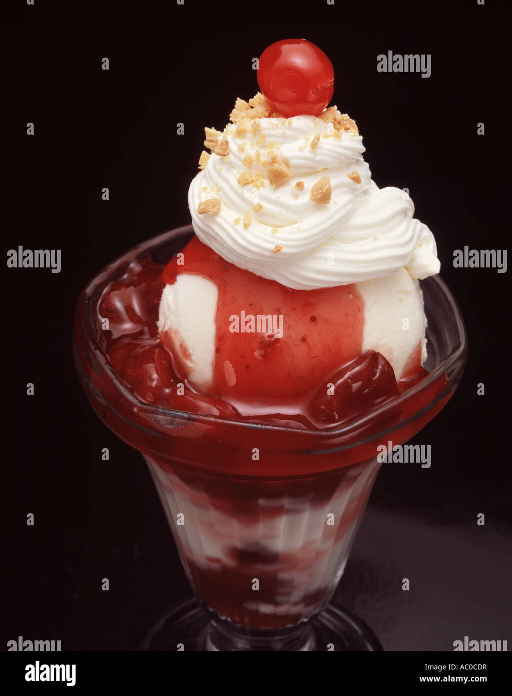 Close up strawberry ice cream sundae dimanche plat en verre crème fouettée saupoudrer de noix vanille sauce Banque D'Images