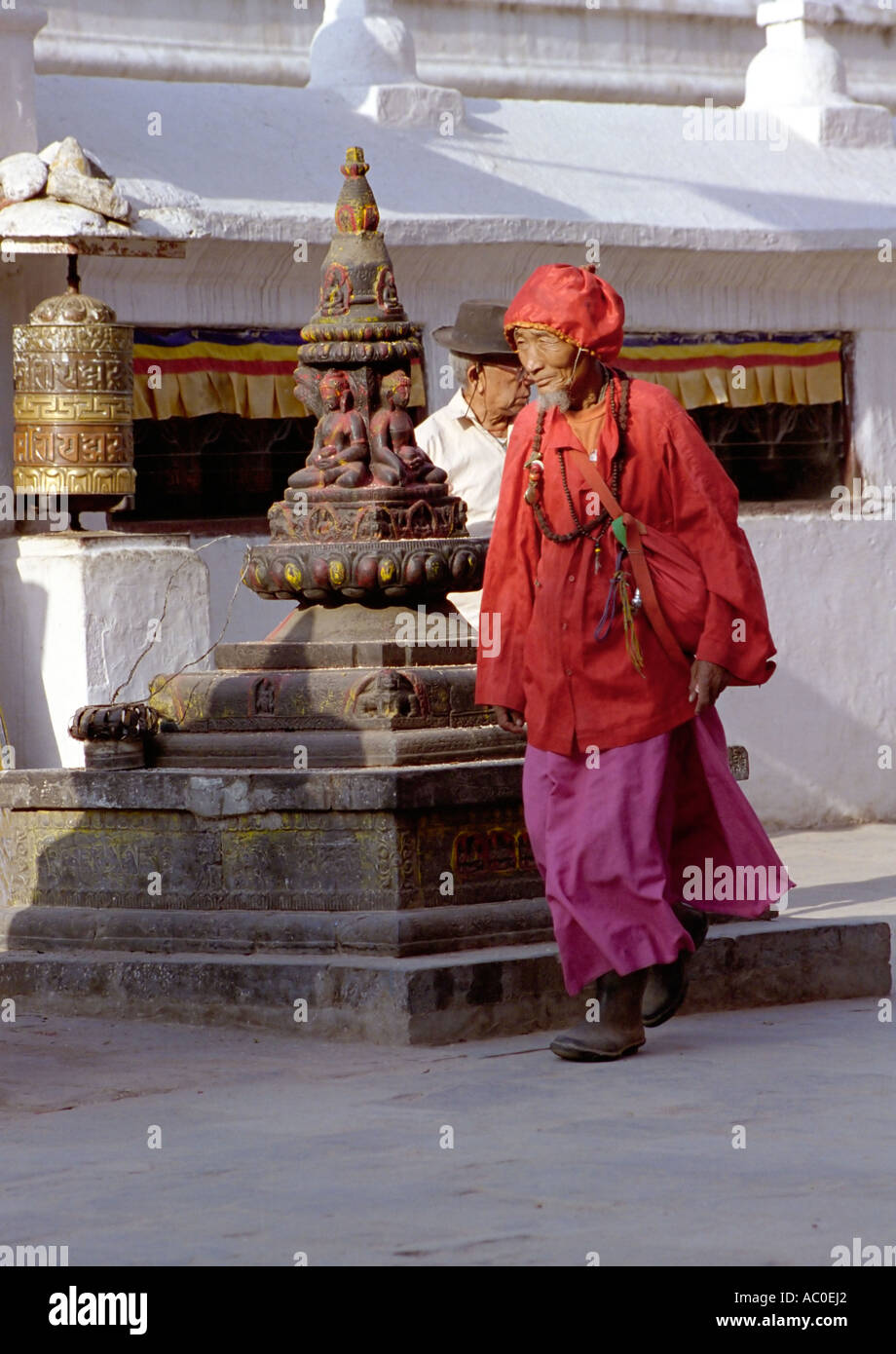 Vieil homme en rouge marche autour du stupa de Bouddhanath près de Katmandou Népal Asie du Sud Banque D'Images
