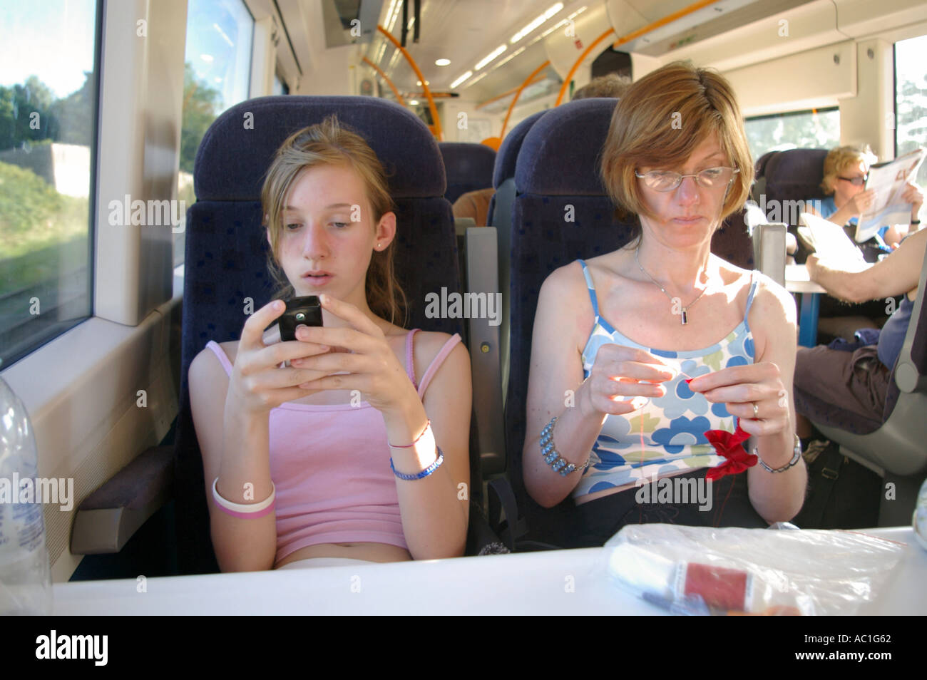 Mère et fille couture faire ennuyer faisant des jeux sur téléphone mobile sur British train Banque D'Images