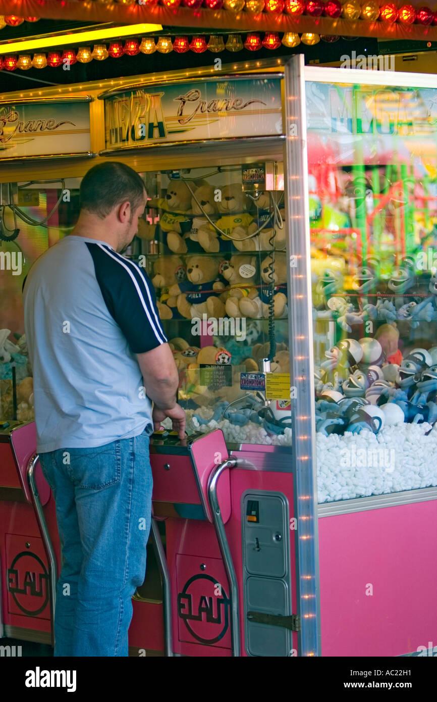 Parc d'homme jouant de la machine pour rempli de peluches Banque D'Images