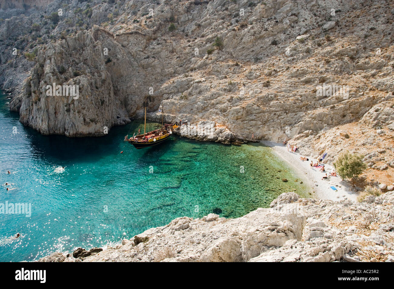 La natation de personnes dans une baie de Kalymnos à côté d'un bateau à voile en Grèce Banque D'Images