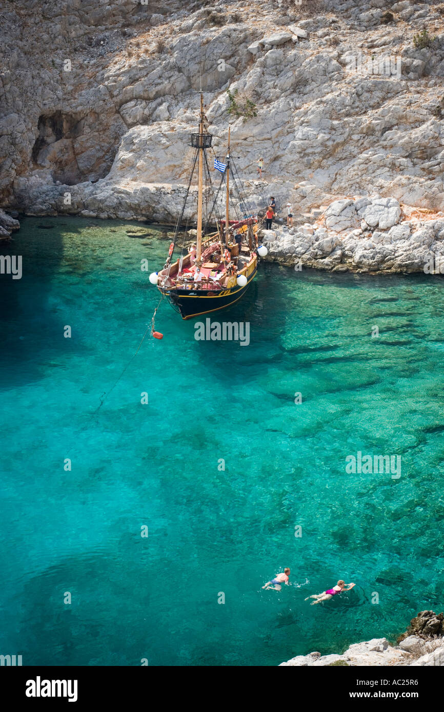 La natation de personnes dans une baie de Kalymnos à côté d'un bateau à voile en Grèce Banque D'Images