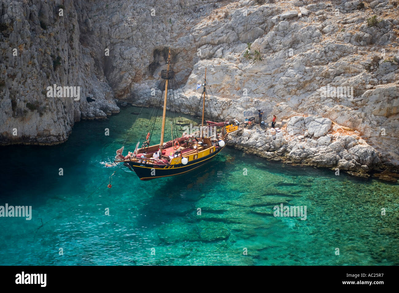 La natation de personnes dans une baie de Kalymnos à côté d'un bateau à voile en Grèce Banque D'Images