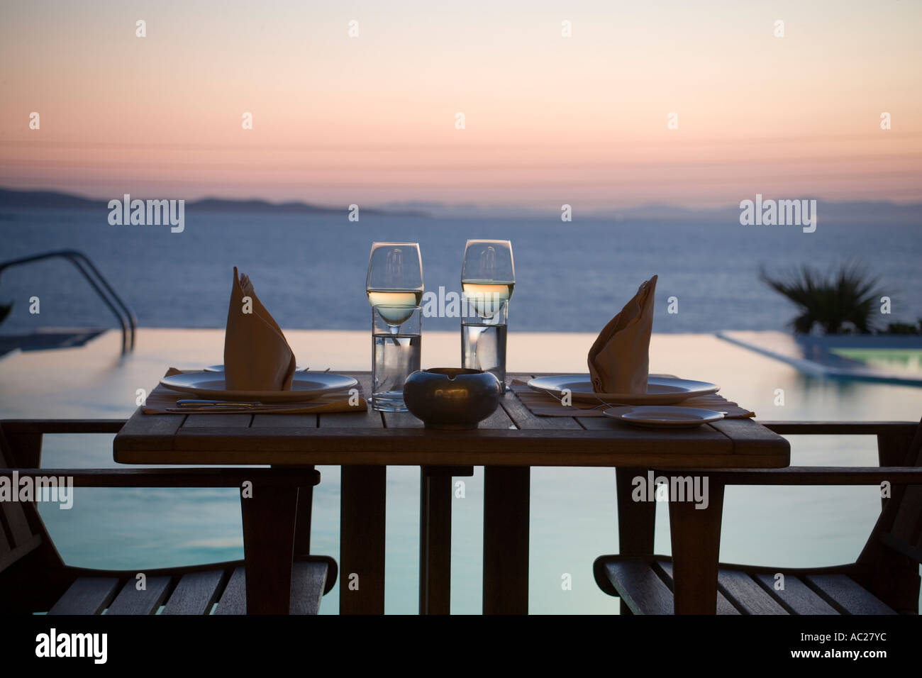 Sertie tables au bord de la piscine d'eau douce de l'Apanema Resort Hotel Resort dans la soirée la ville de Mykonos Mykonos Grèce Banque D'Images