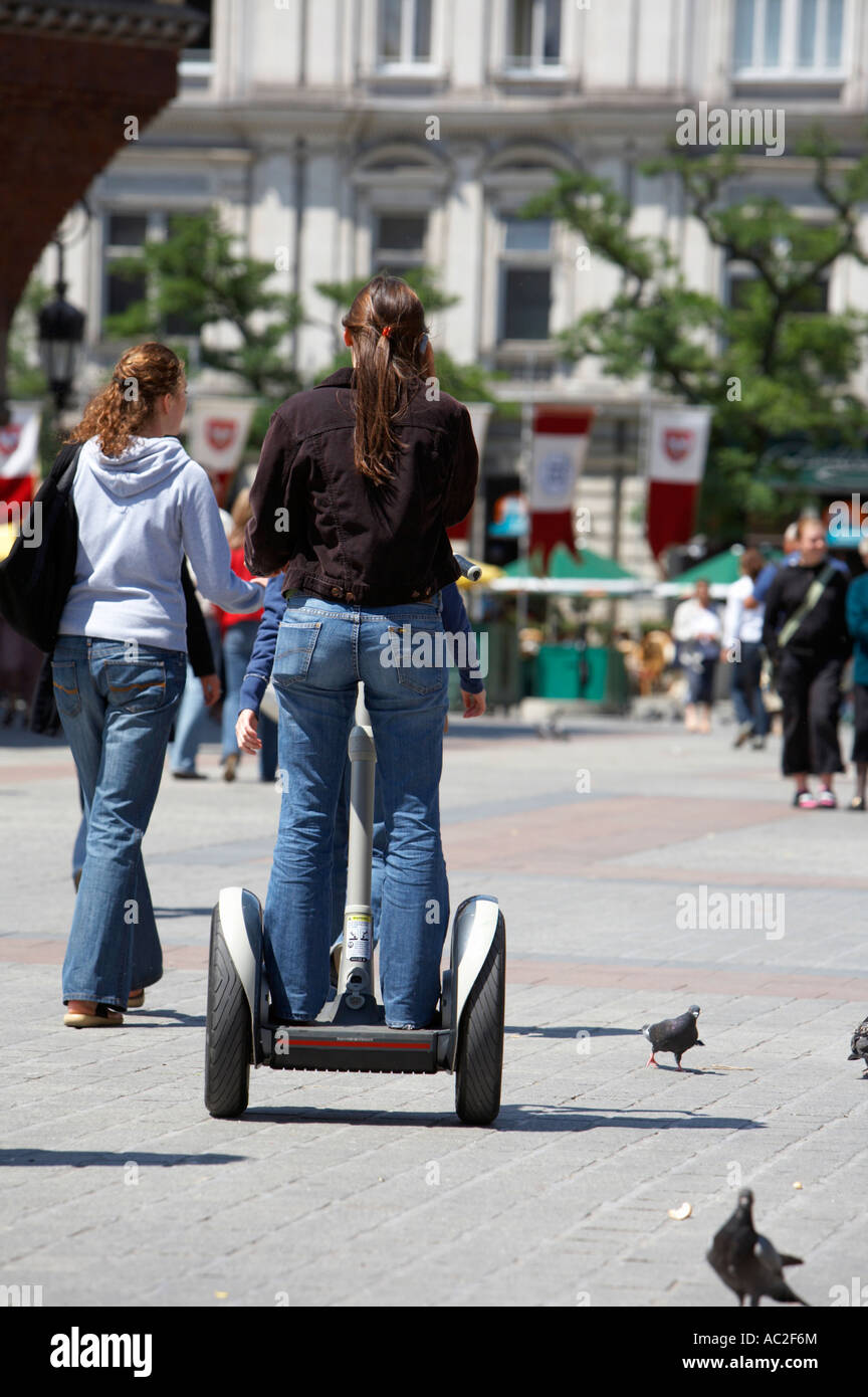 Vue arrière de la fille sur le transport personnel Segway distribuant des dépliants publicitaires pour Rynek Glowny discothèque locale Banque D'Images