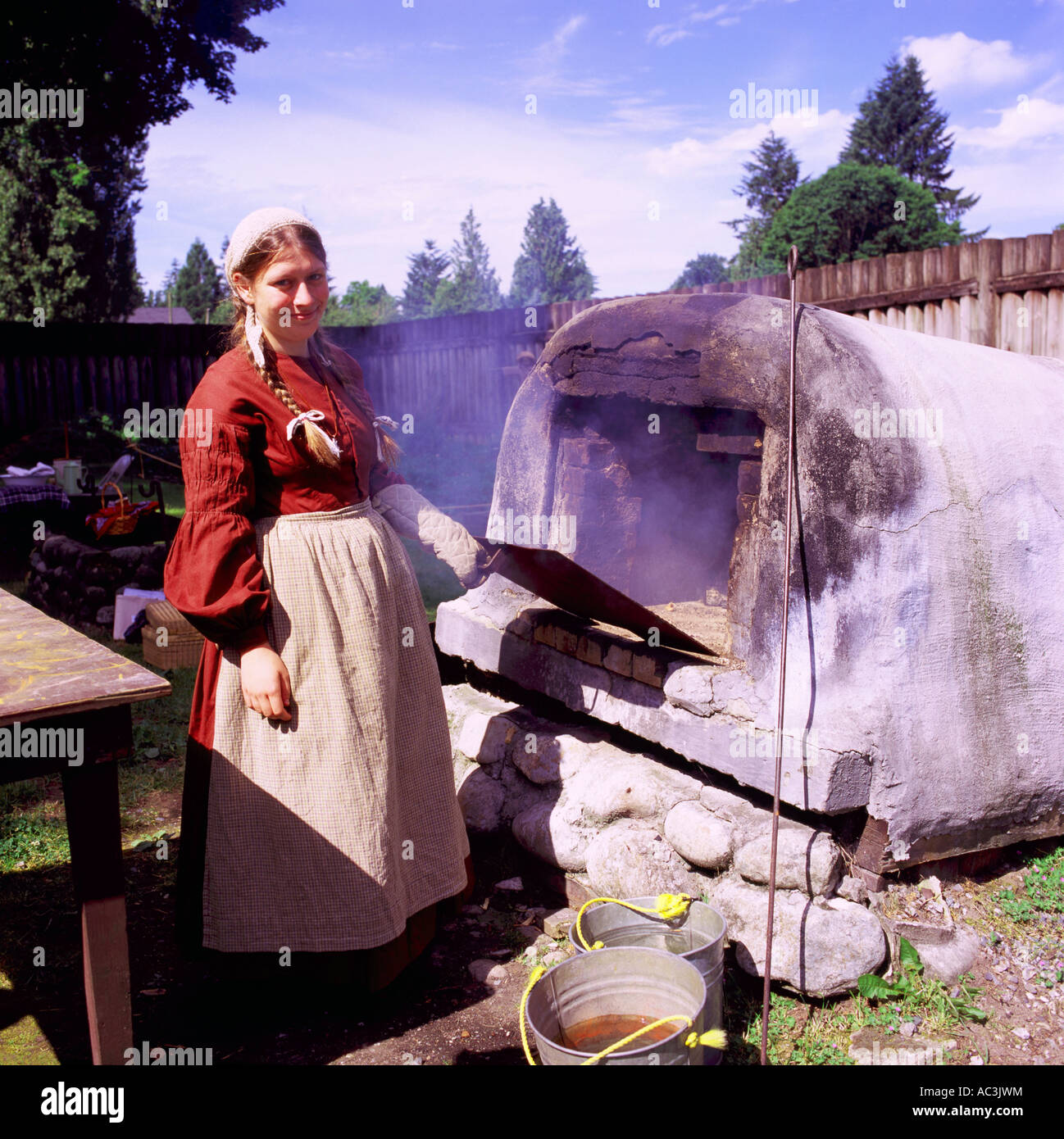 Femme de la reconstitution médiévale la cuisson du pain dans le vieux four en plein air au lieu historique national du Fort Langley, BC, British Columbia, Canada Banque D'Images