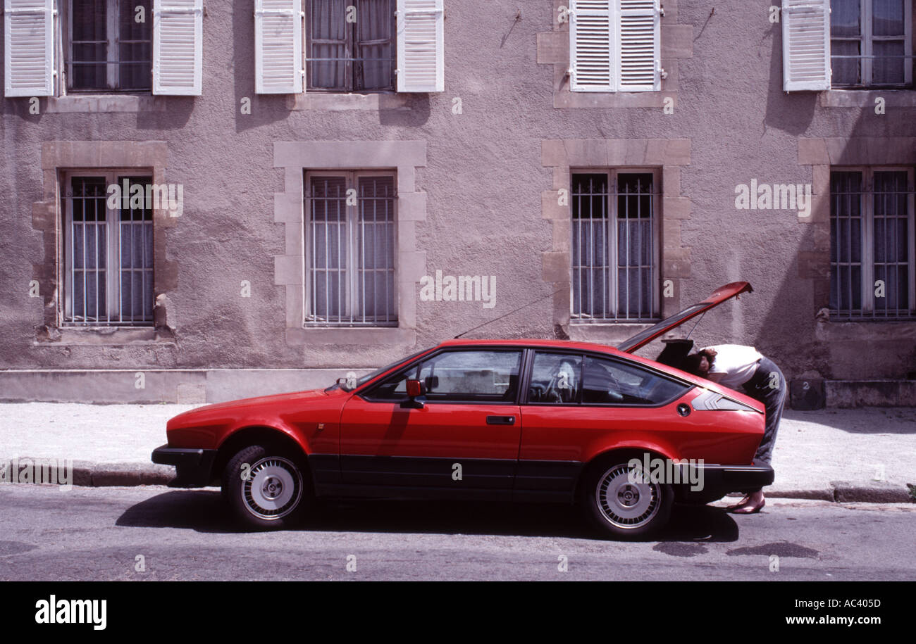 Woman bending over et charger des bagages dans le coffre d'une Alfa Romeo GTV coupé sport Banque D'Images