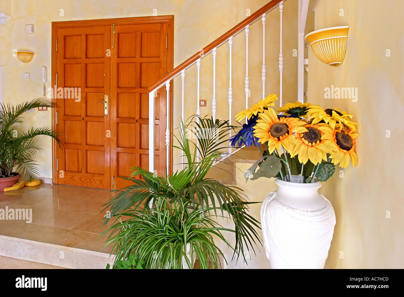 Intérieur jaune vif d'une grande villa escaliers et porte avant avec des tournesols Banque D'Images