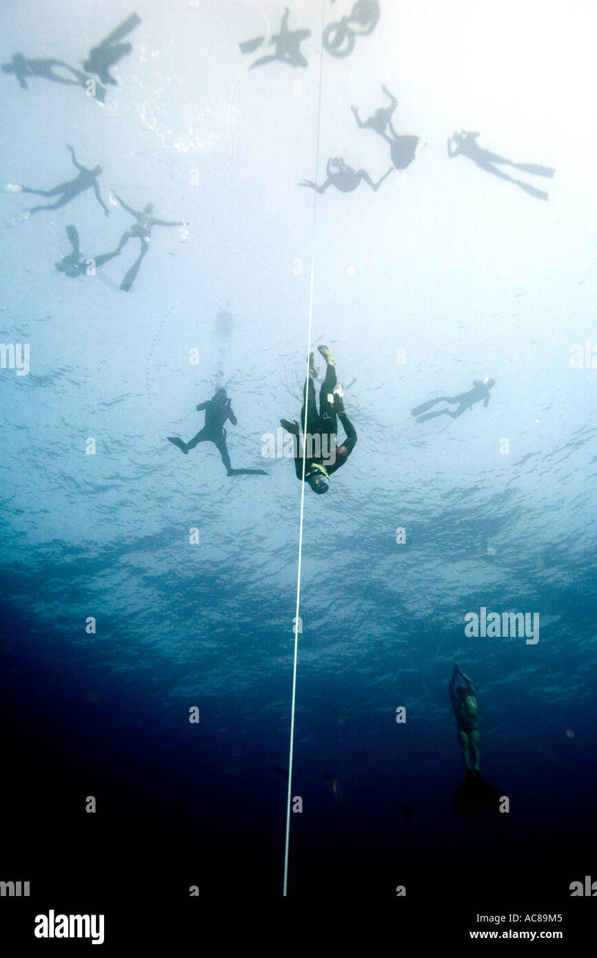 Un free diver remonte à la surface après avoir pratiqué au-dessous d'autres plongeurs libres flottant à la surface Banque D'Images