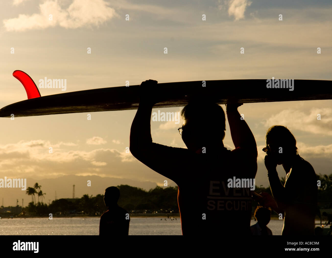 Silhouette of man holding surfboard at sunset Banque D'Images