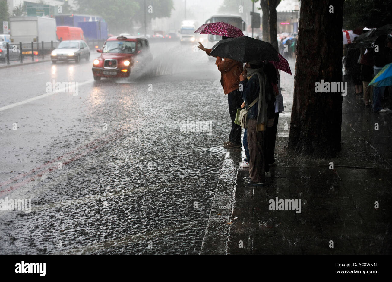 Personnes debout à côté d'un inondés Marylebone Road à Londres essaie d'attraper un taxi dans une tempête de pluie Banque D'Images