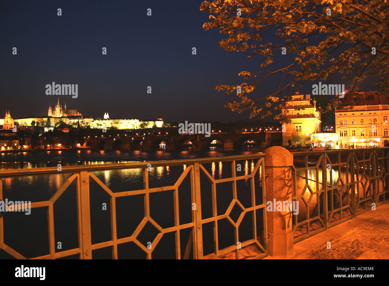 Château de Prague vu de la rive la nuit, la rivière Vltava et le pont Charles sont vus au premier plan. Banque D'Images