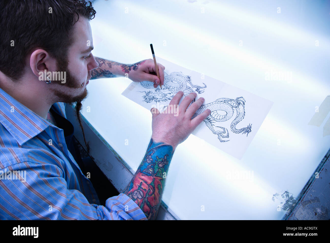 Homme de race blanche artiste de tatouage tatouage dessin sur table  lumineuse Photo Stock - Alamy