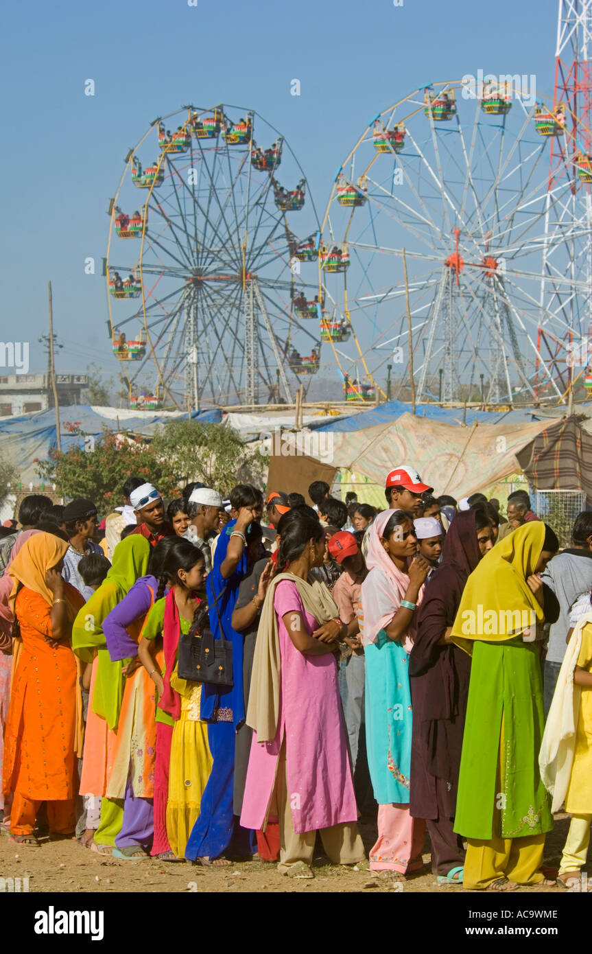 Une longue file d'attente des femmes et des jeunes filles vêtues de leurs plus beaux vêtements attendre patiemment la nourriture gratuite au Mewar festival. Banque D'Images