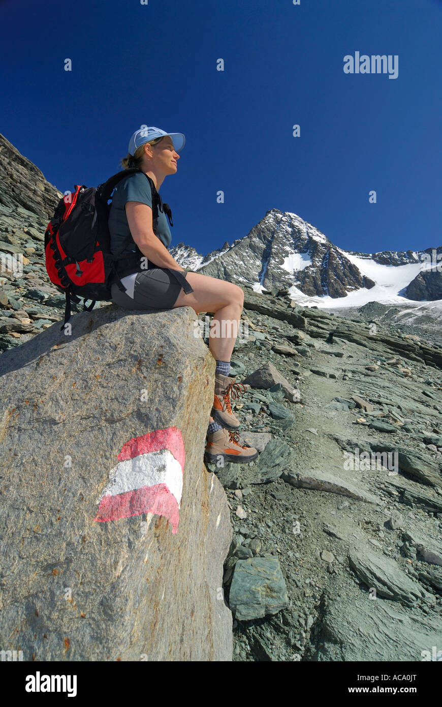 Femme assise à un sentier en face de la crête du Grossglockner, Parc National Hohe Tauern, Tyrol, Autriche Banque D'Images