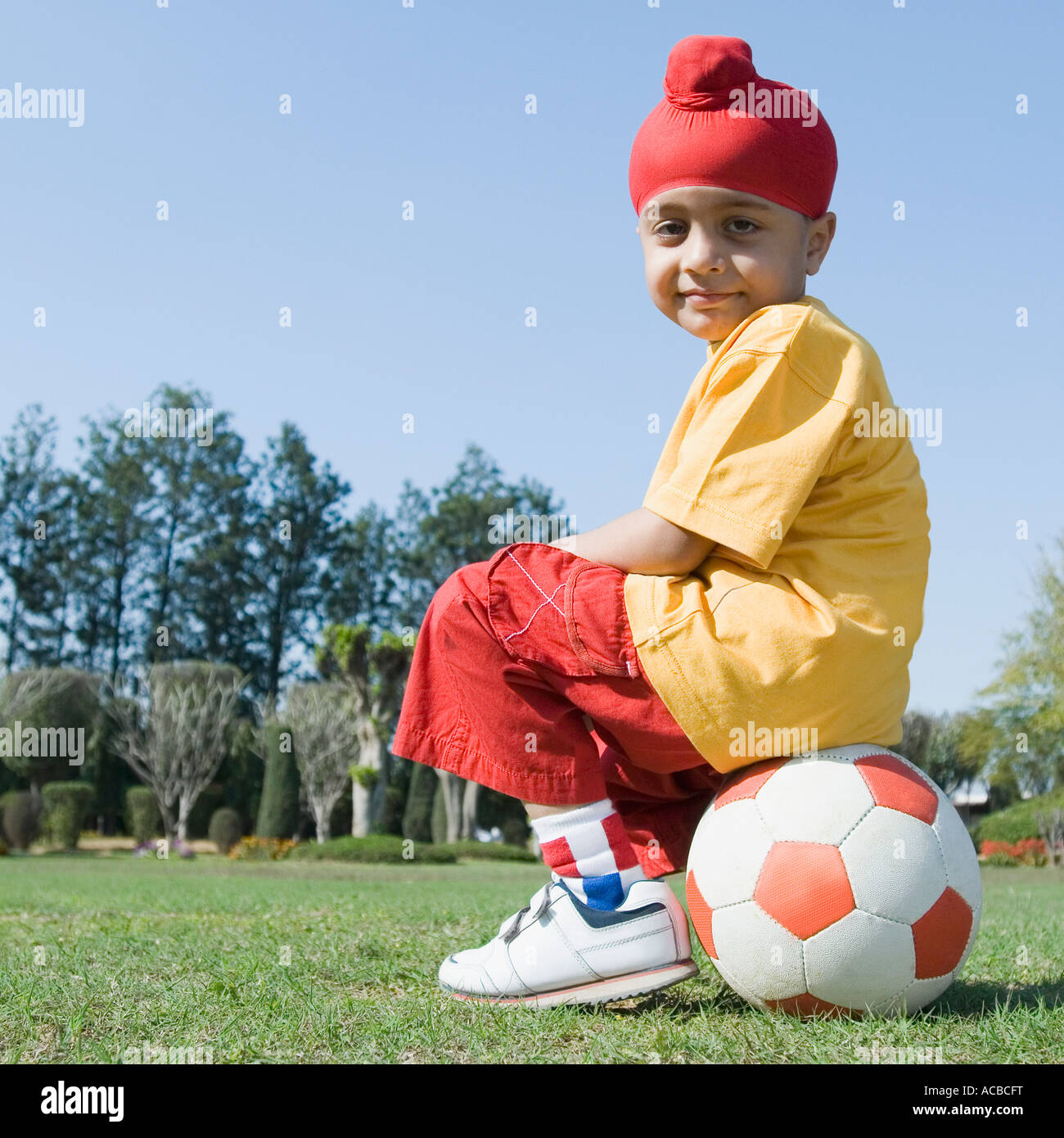 Portrait d'un garçon assis sur un ballon de foot Banque D'Images