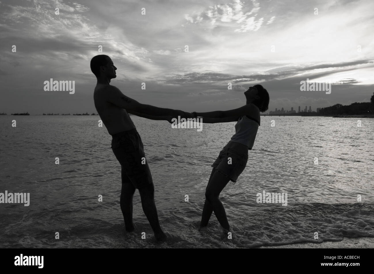Silhouette d'un couple holding hands and standing on the beach Banque D'Images