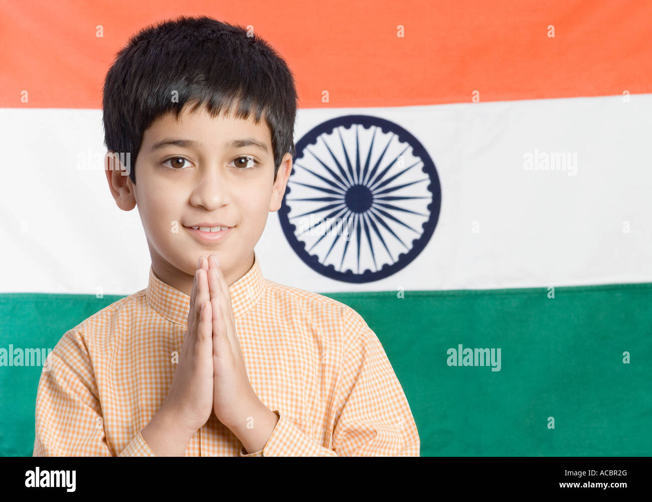 Close-up d'un garçon debout devant le drapeau indien avec ses mains pliées Banque D'Images