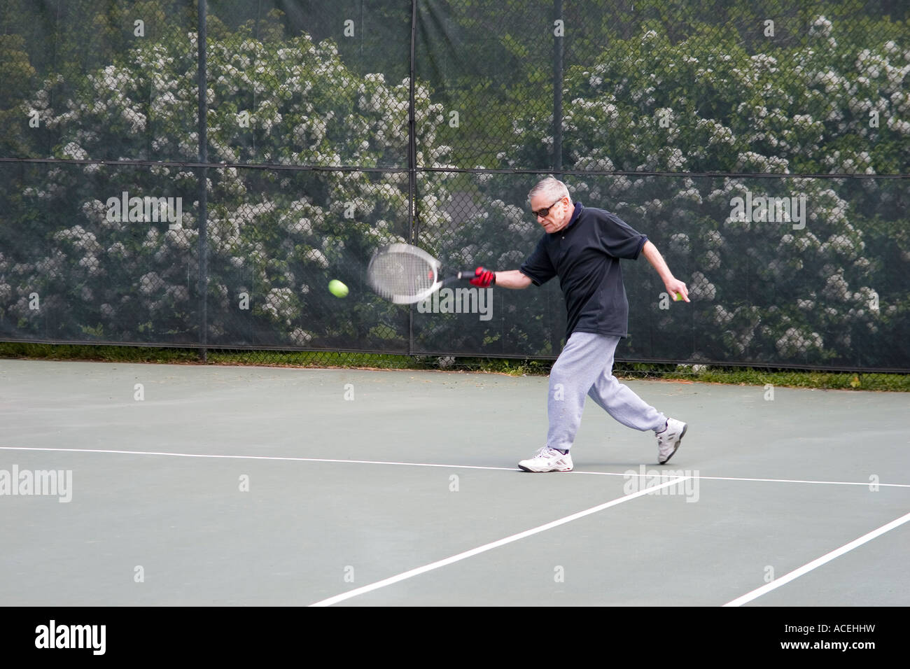 Personnes âgées retired man playing tennis frapper la balle de tennis avec une course de coup droit Banque D'Images