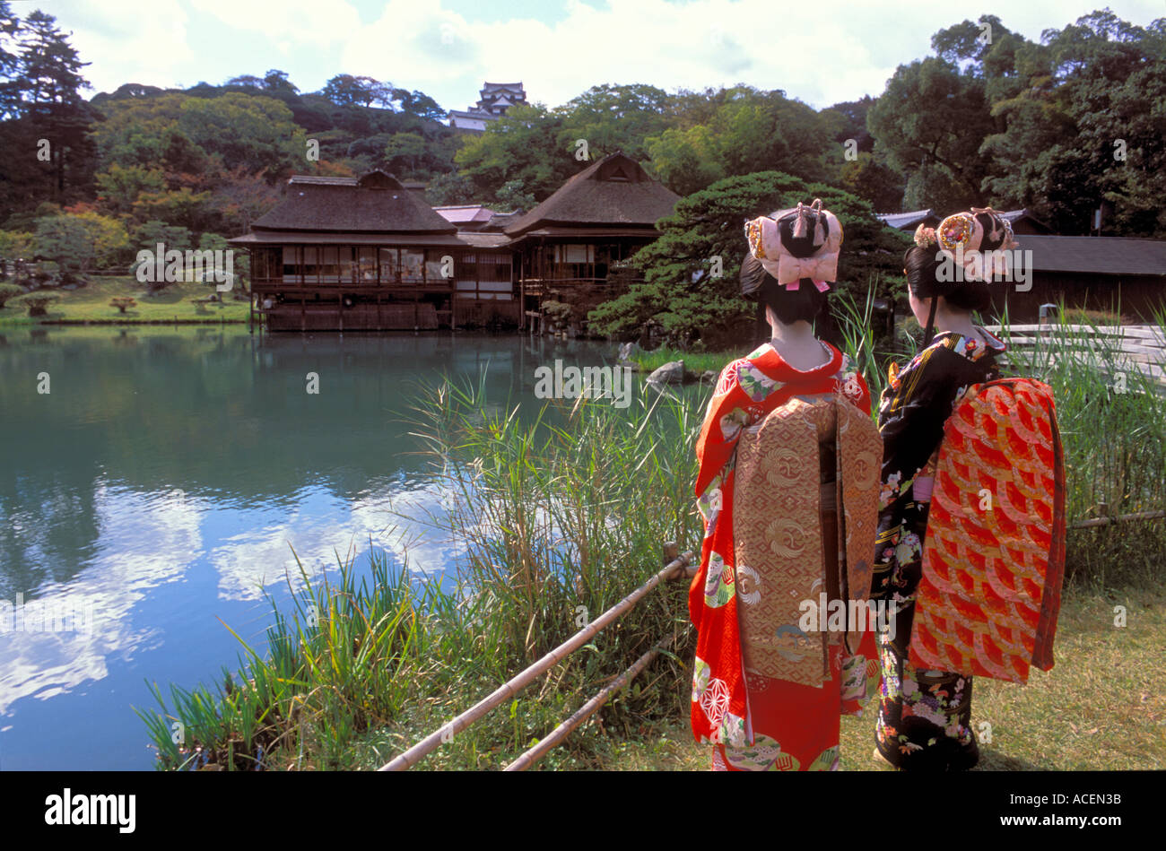 Deux femmes vêtues d'un costume de kimono d'époque de noblesse jouissent d'une vue sur le château et l'étang au jardin Genkyuen à Hikone, au Japon Banque D'Images