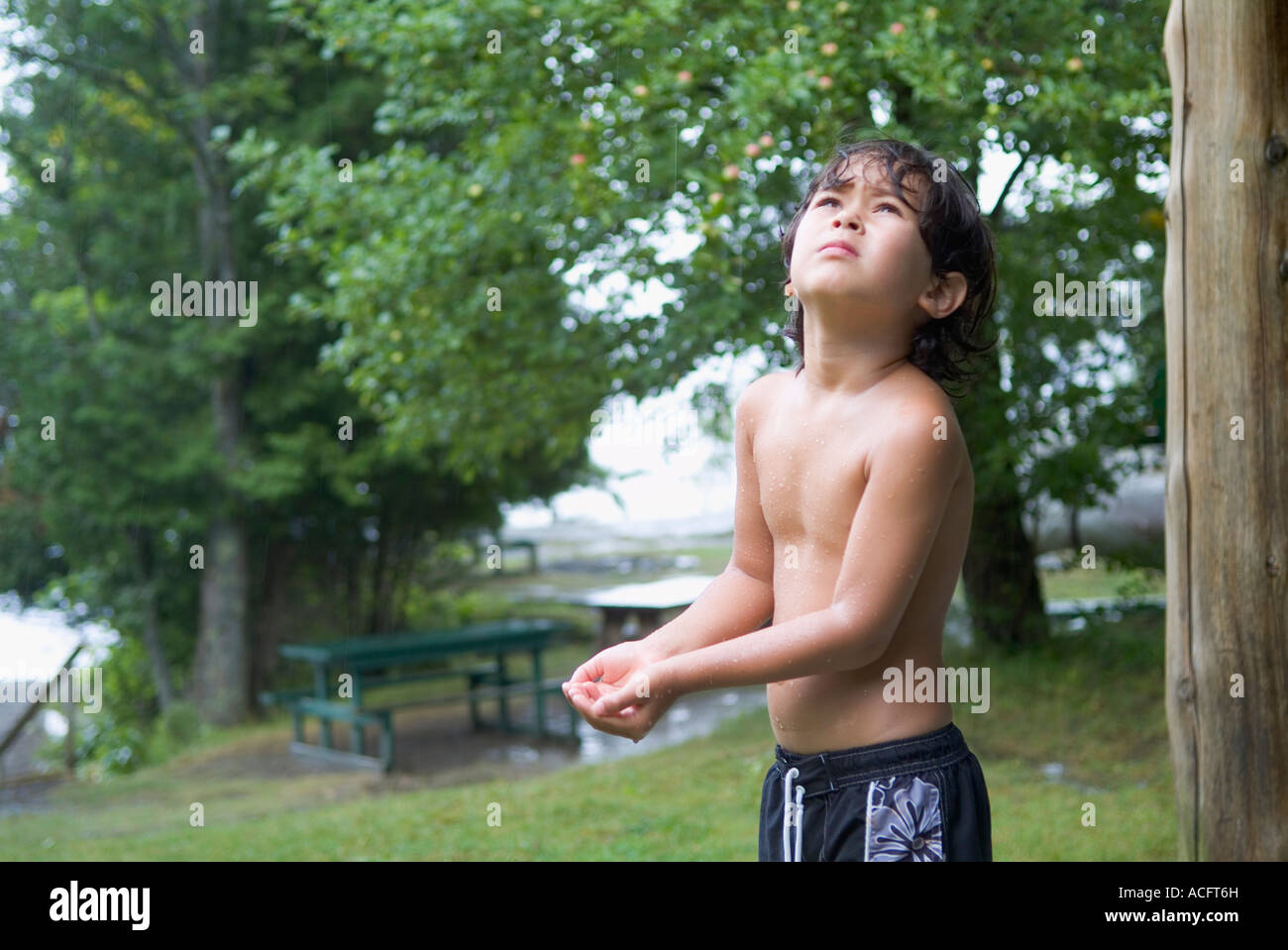 Jeune garçon en maillot à la vers le ciel et attendent d'une pluie. Parution du modèle Banque D'Images