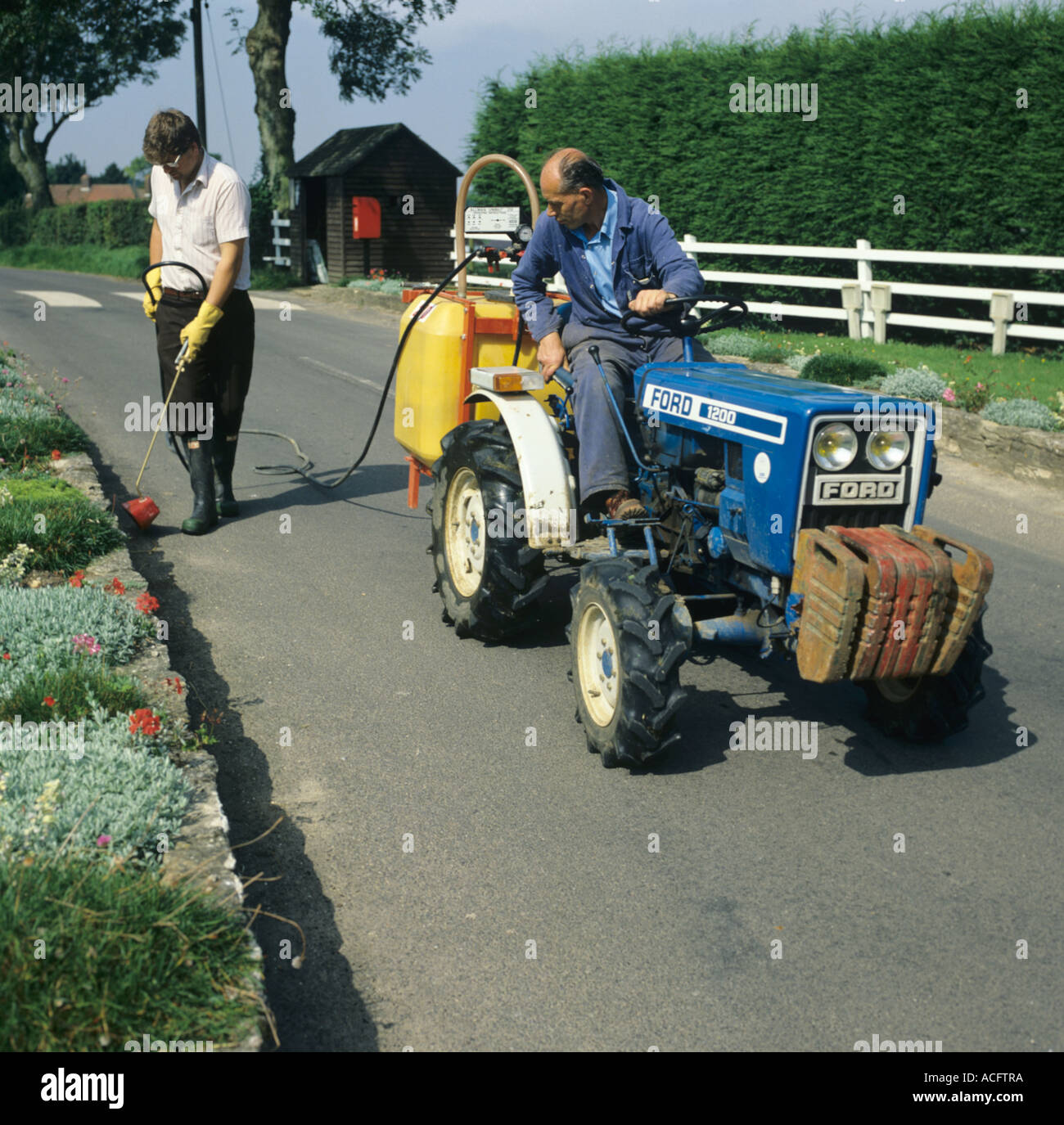 Petit jardin Ford Tracteur avec réservoir de pulvérisation pulvérisation homme marchant sur les mauvaises herbes de l'allée Banque D'Images