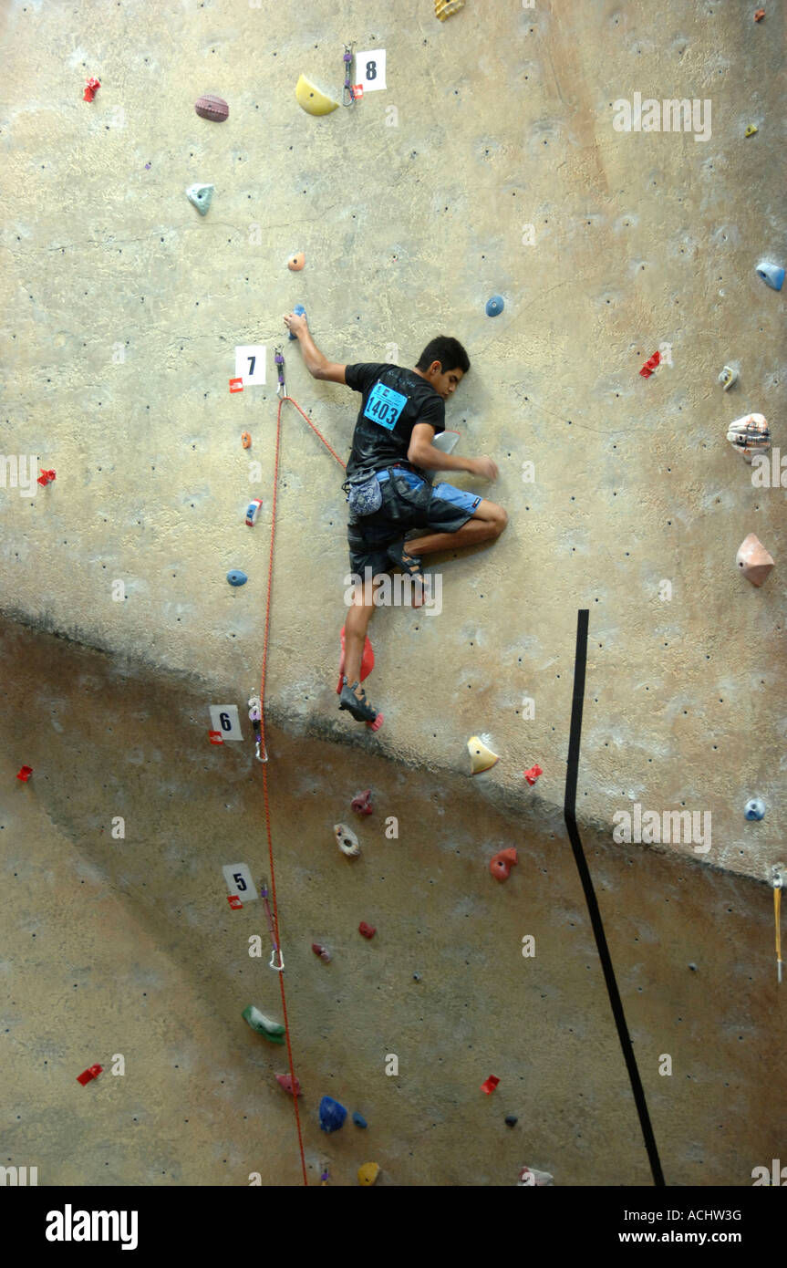 Jeune homme escalade un mur d'escalade à l'installation à une compétition d'escalade Banque D'Images